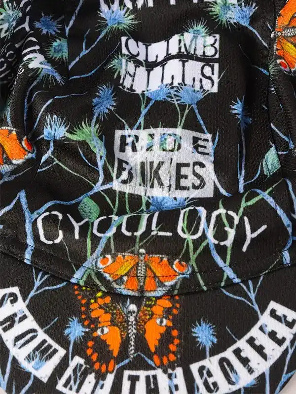 Cycling jersey with 'Climb Hills Ride Bikes' text, butterflies, and thistle print on black fabric