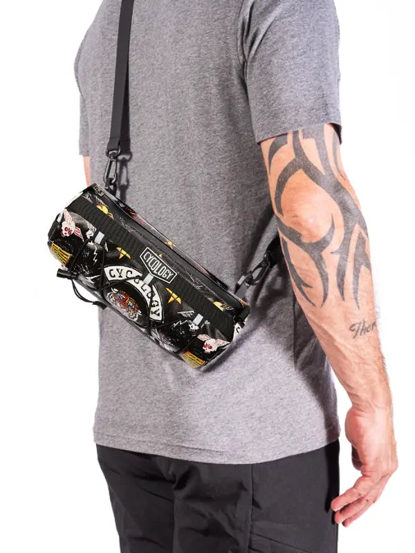 Person wearing a black crossbody bike bag with colorful designs