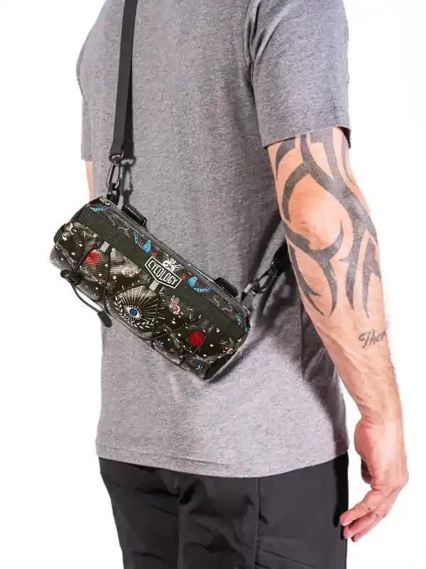 Stylish patterned crossbody bag with eye motifs, worn over shoulder by man in gray tee