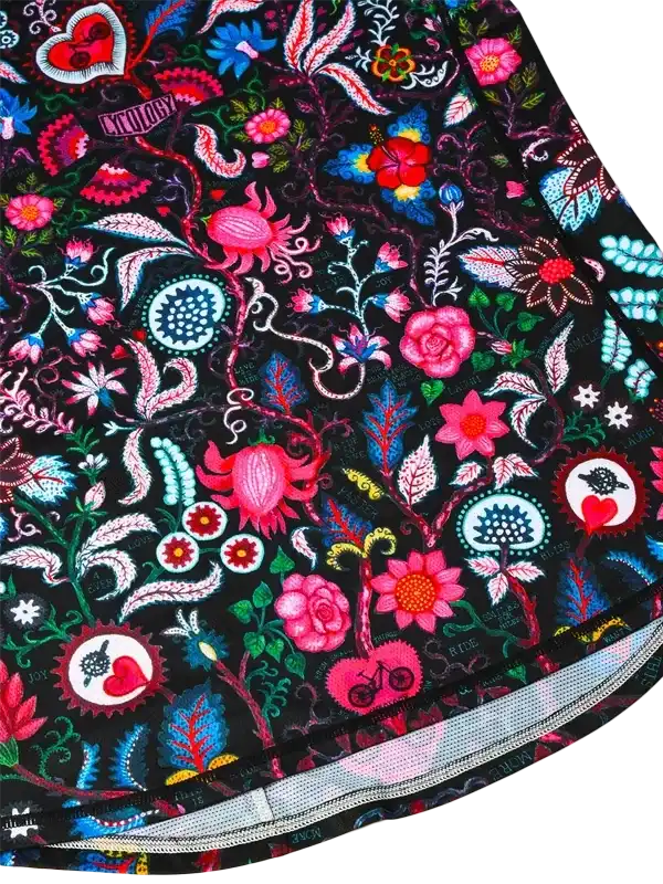 Vibrant floral cycling jersey with bold pink, blue, and red patterns on black fabric, featuring heart and bike motifs.