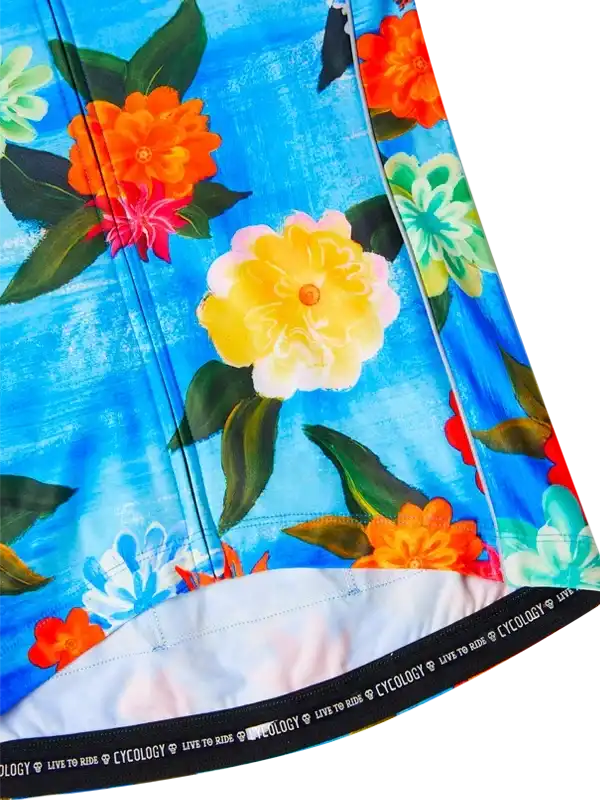 Vibrant floral cycling jersey with bold orange, yellow, and blue blooms on blue background, featuring 'LIVE TO RIDE' hem detail