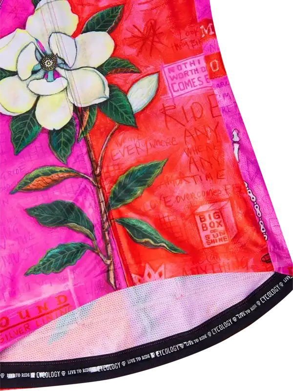 Vibrant pink and red cycling jersey with white magnolia flower print and motivational text, featuring breathable mesh hem.