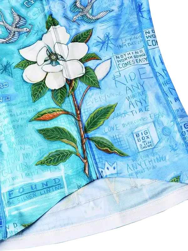 Blue cycling jersey with white magnolia flower, green leaves, and motivational text print