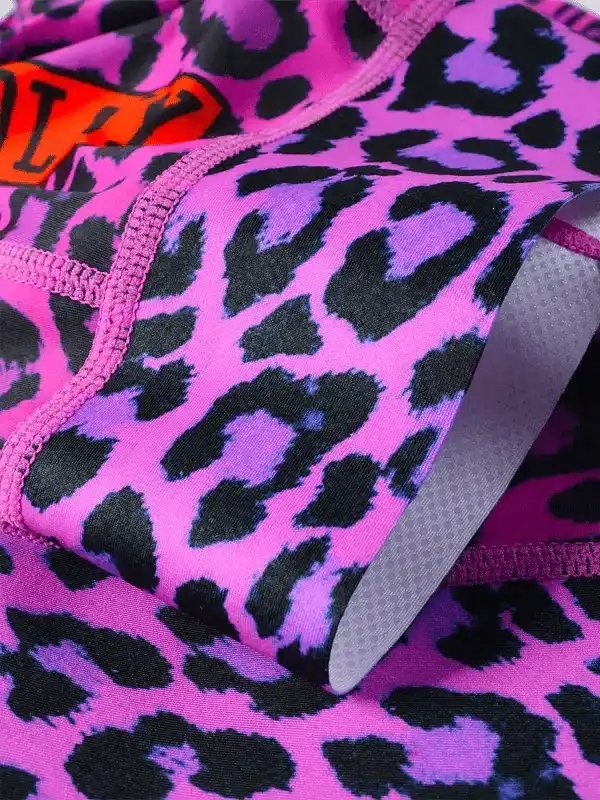 Pink leopard print cycling shorts with black spots and orange logo detail
