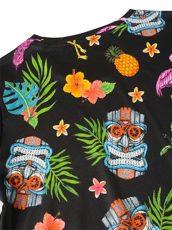 Tropical print cycling jersey with tiki masks, pineapples, and hibiscus flowers on black fabric