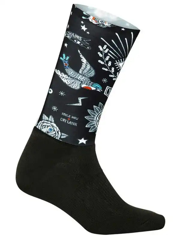 Black cycling sock with tattoo-style bird, stars, and 'Smile Now Cry Later' design