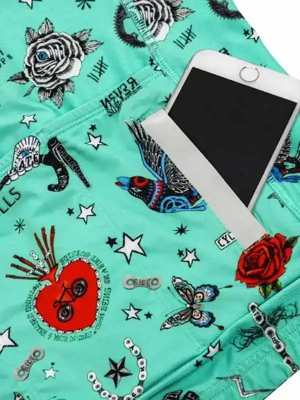 Mint green cycling shorts with tattoo-style roses, stars, and bird print, featuring phone pocket