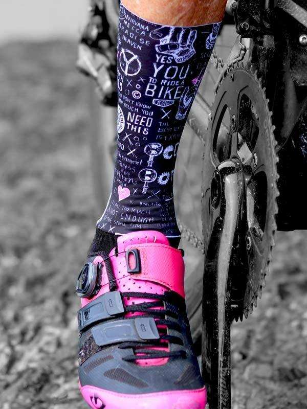 Cycling socks with fun bike-themed graphics paired with pink and black cycling shoes on a bike pedal