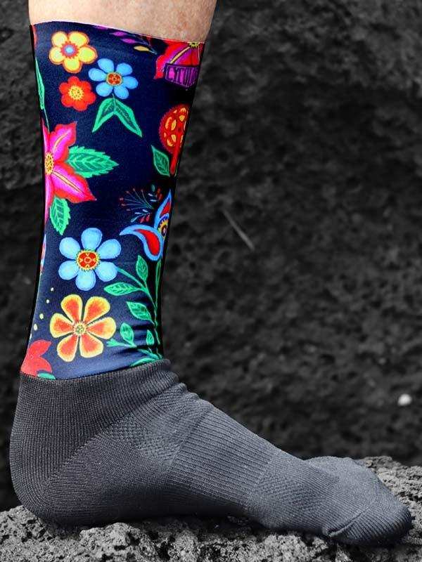 Colorful floral cycling sock with vibrant flowers on dark background, worn on foot outdoors