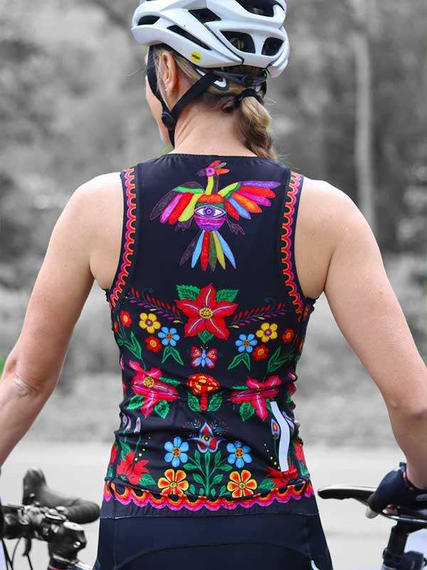 Woman cycling in black tank top with colorful floral and bird embroidery, wearing white helmet
