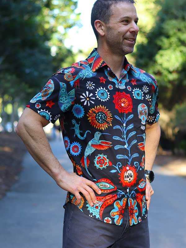 Man wearing vibrant, patterned short-sleeve cycling shirt with floral and skull designs outdoors