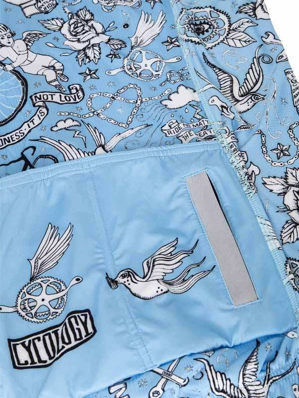 Light blue cycling shorts with tattoo-style bird, rose, and gear print, reflective strip, and Cycology logo