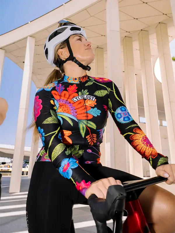 Person wearing a black floral long sleeve Winter cycling jersey with a helmet, sitting on a bicycle