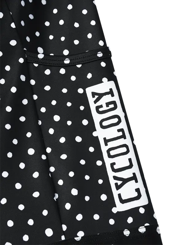 Black and white polka dot  cargo cycling shorts with a vertical white brand label reading 'CYOLOGY' on the lower left leg, shown from a side profile view  with a pocket against a plain white background.