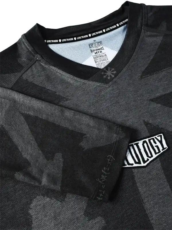 Men's black cycling jersey with geometric pattern, V-neck, and brand patch detail