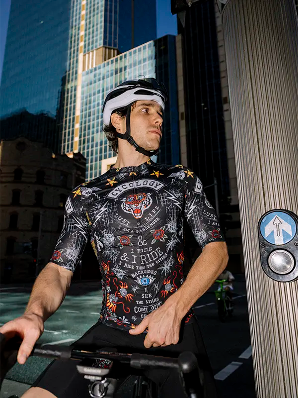 Person wearing a Black men's cycling jersey with colorful graphics and text, featuring a tiger and various designs.