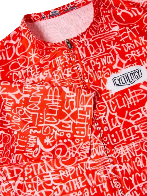 Vibrant red cycling jersey with white graffiti-style print, featuring bold text and Cycology logo patch.