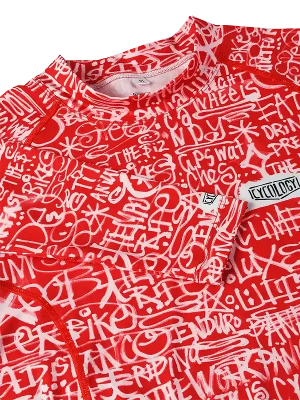 Red cycling jersey with white graffiti-style text design, featuring bike and ride phrases