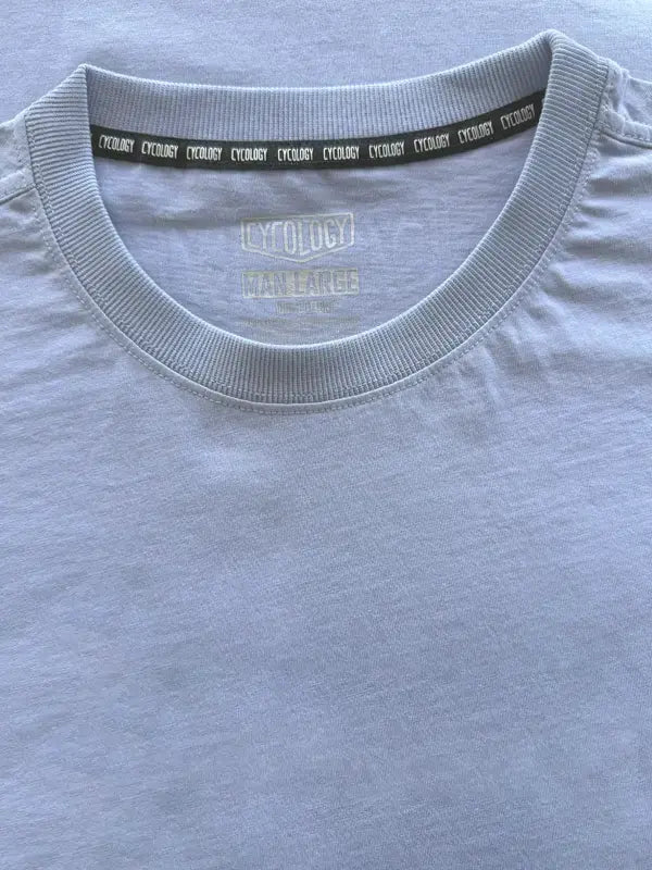 Close-up of a light blue t-shirt with a brand logo on the collar.