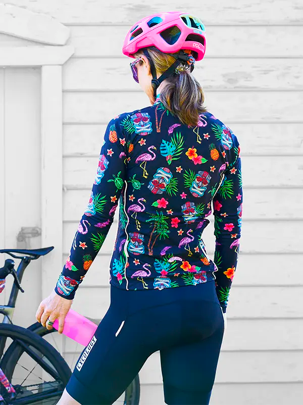 Person wearing a Molokai Black Women's Winter Long Sleeve Cycling Jersey with colorful tropical pattern featuring skulls, flamingos, and flowers.