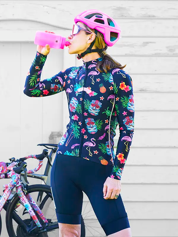Person wearing a Molokai Black Women's Winter Long Sleeve Cycling Jersey with colorful tropical pattern featuring skulls, flamingos, and flowers.