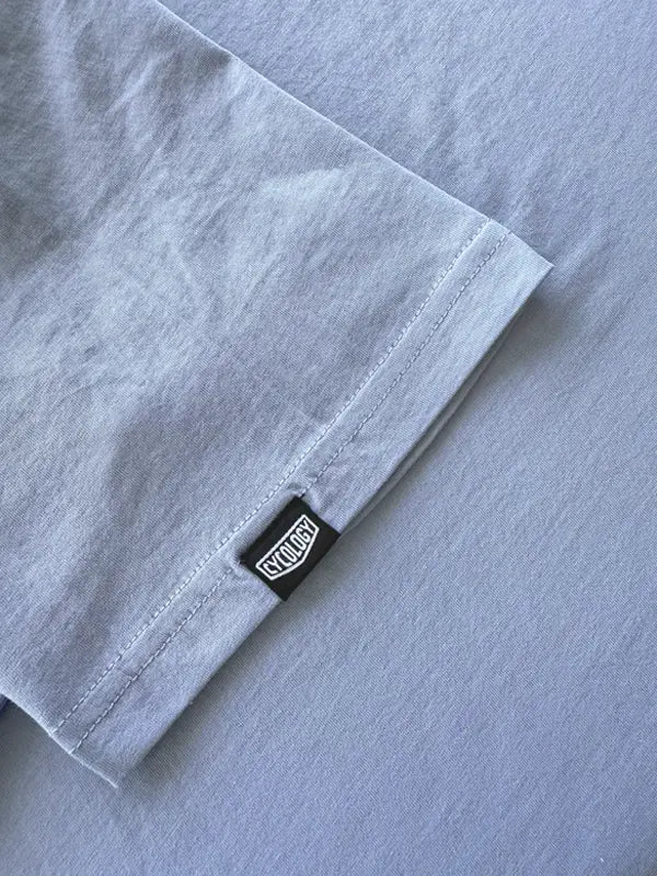 Close-up of a blue T shirt with a small brand label on the sleeve