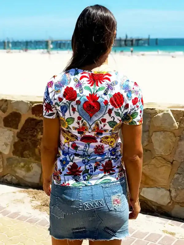 Woman wearing floral cycling jersey with heart design, beach backdrop, denim skirt
