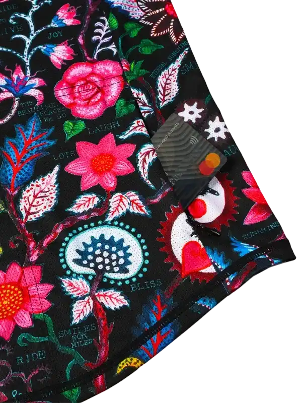 Vibrant floral cycling jersey with bold pink roses, motivational phrases, and colorful botanical print on black fabric.