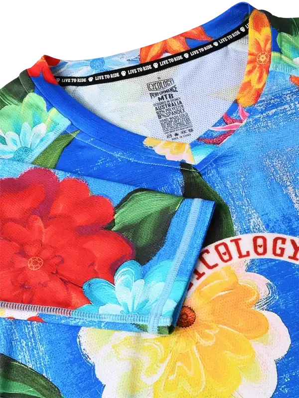 Vibrant floral cycling jersey with bold red, yellow, and blue blooms, performance fabric, and 'LIVE TO RIDE' tag