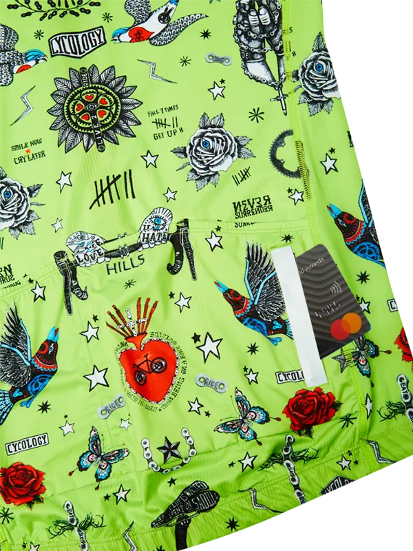 Green fabric with colorful tattoo-style designs including roses, hearts, and stars.