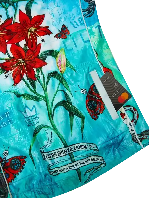 Vibrant cycling shorts with red lilies, butterflies, and bold text on turquoise fabric