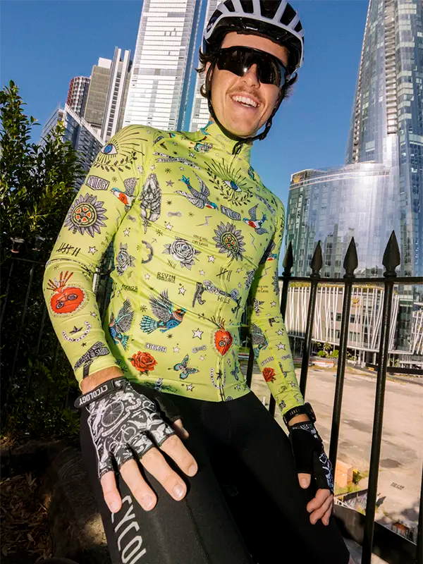 Person wearing a colorful cycling jersey with tattoo design in an urban setting