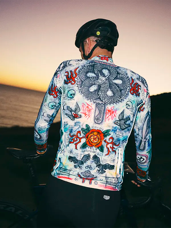 Person wearing a colorful cycling jersey with intricate designs against a sunset background