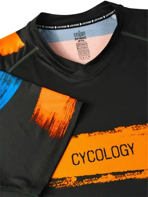 Black cycling jersey with bold orange and blue brushstroke design, featuring 'CYCOLOGY' text and performance fabric details