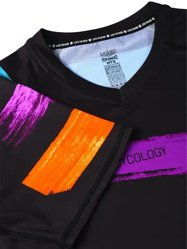 Black cycling jersey with vibrant purple and orange brushstroke design, performance fabric, and 'LIVE TO RIDE' tag