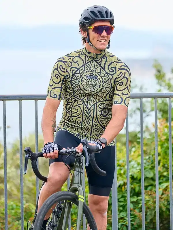 Man wearing patterned cycling jersey and shorts, riding road bike outdoors