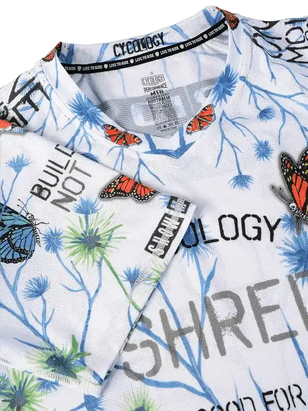 White cycling jersey with butterfly and dandelion print, bold text design, breathable fabric