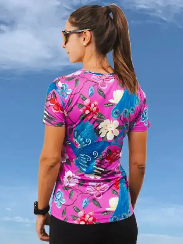 Woman wearing vibrant pink and blue floral cycling jersey with bird design, ideal for bike rides
