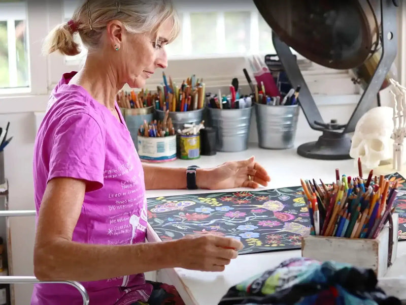 Woman designing floral cycling apparel in studio with colorful pencils and art supplies