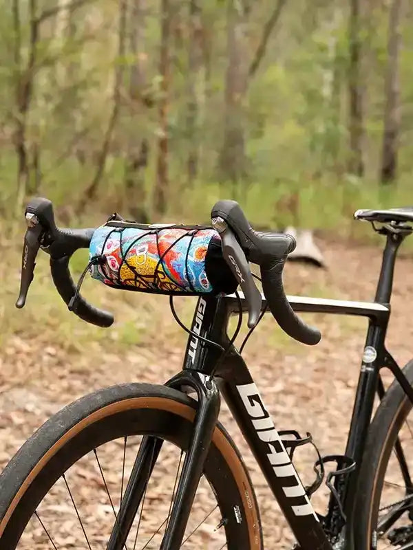 Colorful cycling frame bag on bike handlebars in forest trail setting