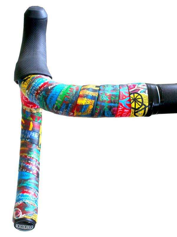 Colorful graffiti-style cycling handlebar tape with black end plugs, featuring vibrant patterns and text for road bikes.
