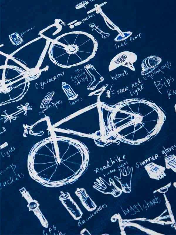 Cycling apparel design with bikes, helmets, gloves, and gear sketches on navy blue fabric