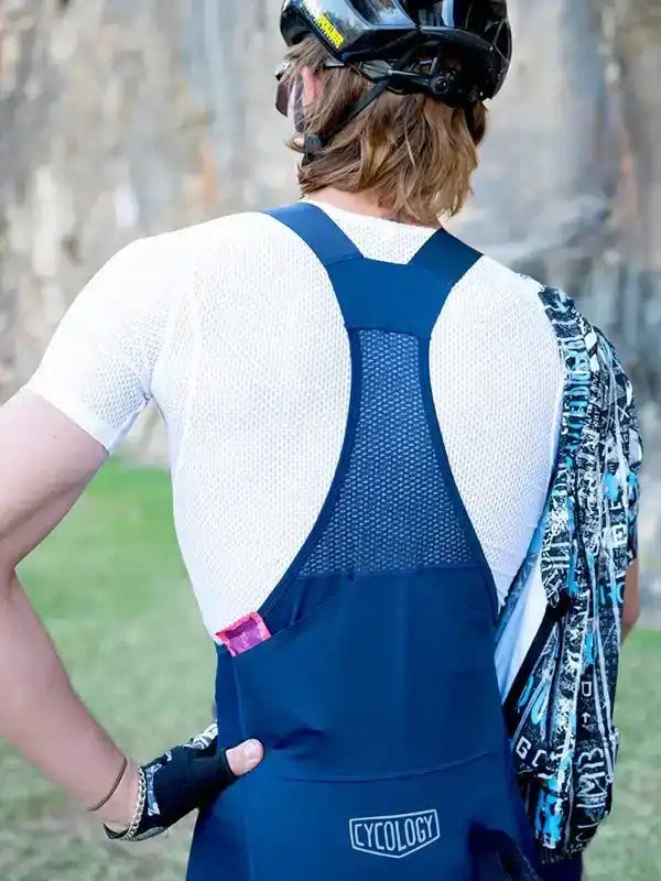 Man wearing blue cycling bib shorts with mesh back panel and white jersey, outdoors