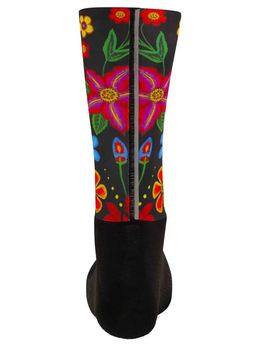 Colorful floral cycling sock with black base, vibrant pink, red, yellow, and blue flowers, green leaves, and reflective strip