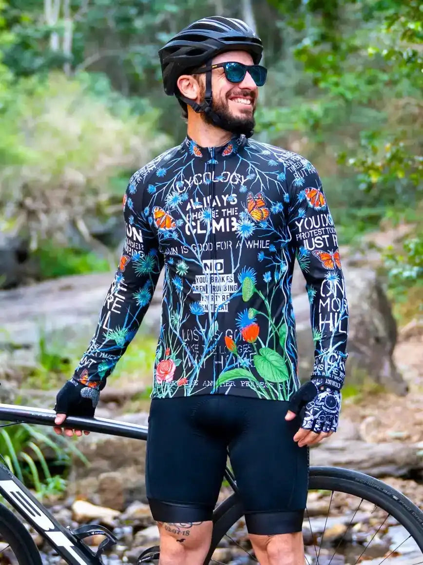 Men's long sleeve cycling jersey with floral and butterfly print, worn on forest trail with bike