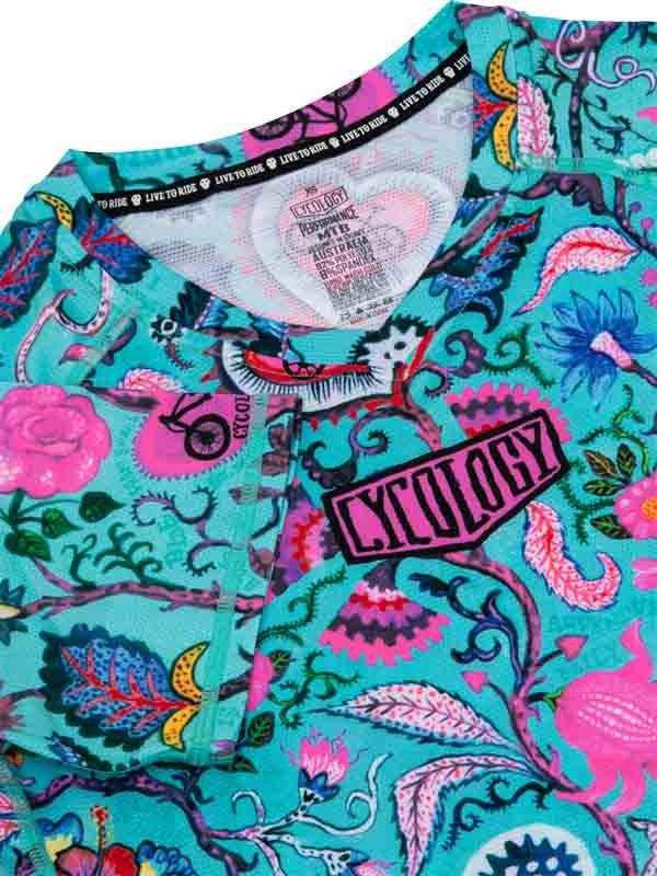Vibrant floral cycling jersey with bold pink and teal patterns, featuring a 'Cycology' logo and performance tag.