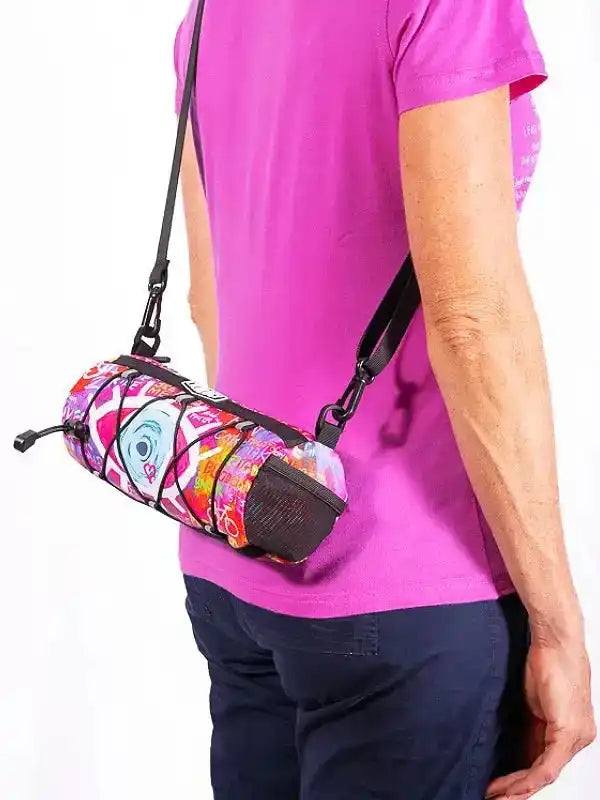 Colorful patterned cycling waist bag with black straps worn by person in pink shirt