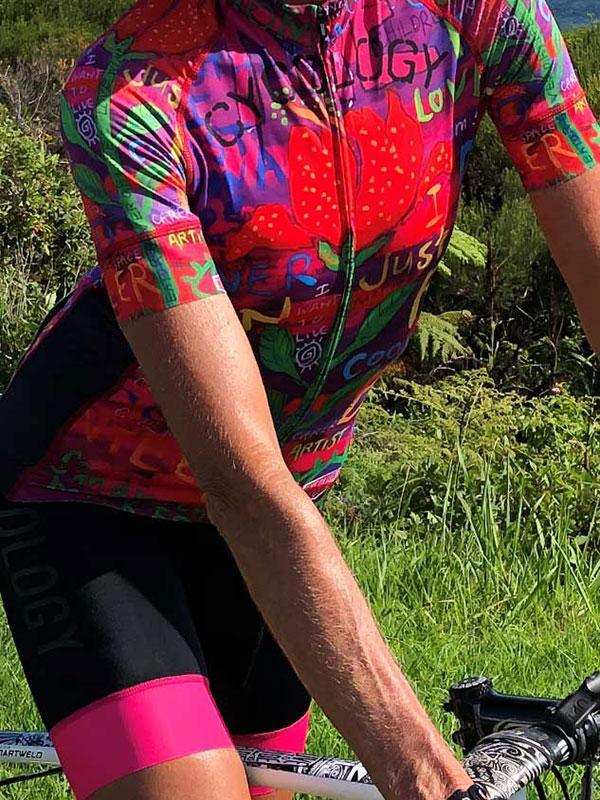 Vibrant cycling jersey with floral and graffiti art, worn by cyclist on outdoor trail